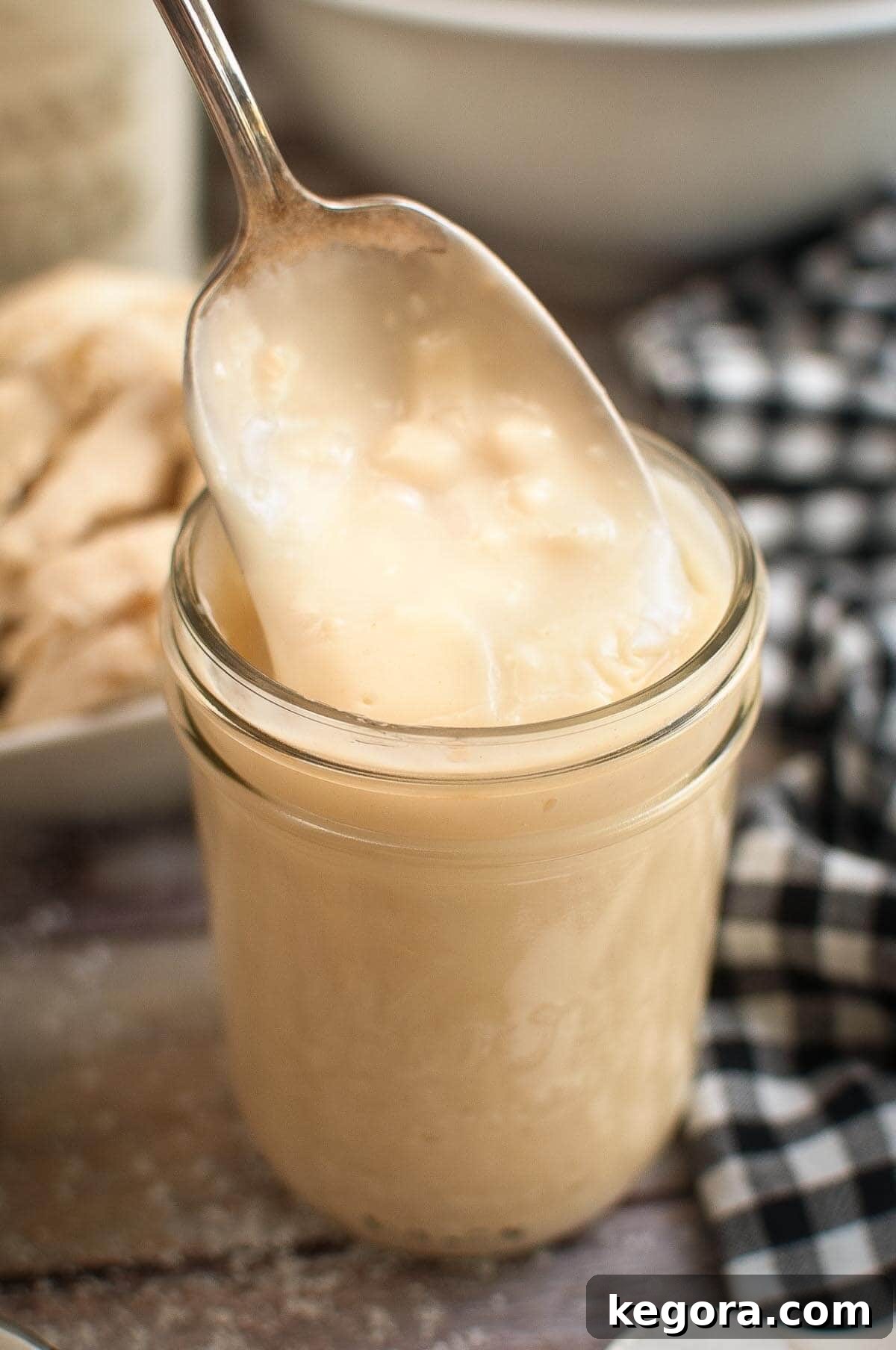 Homemade Condensed Cream of Chicken Soup in a jar with some on a spoon.