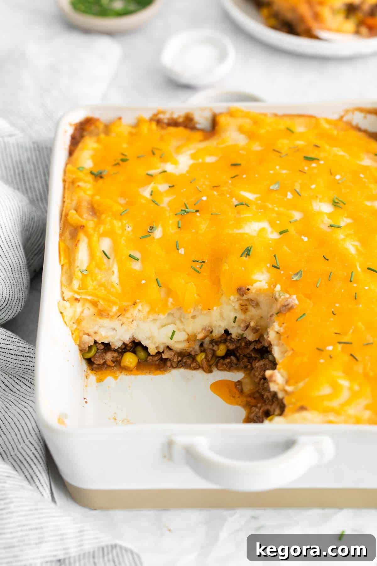 Wholesome Gluten-Free Shepherd's Pie 11 A dish of shepherd's pie with a portion scooped out, showcasing the layers of meat and potatoes.