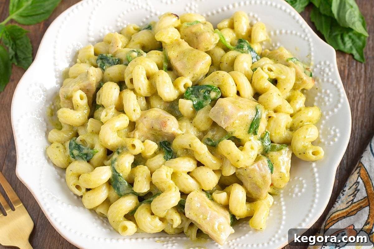 A close-up shot of a bowl of creamy pesto chicken pasta, highlighting the texture of the sauce and the pasta.