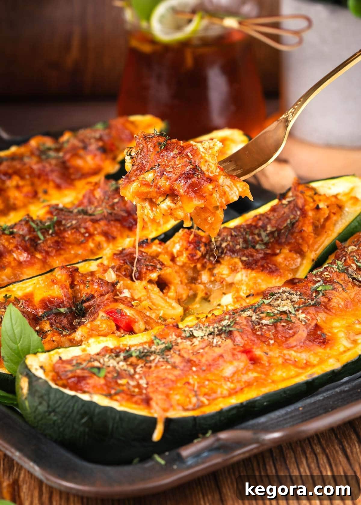 A fork taking a bite of a cheesy stuffed zucchini boat, showing the layers of cheese and filling, ready to be enjoyed.
