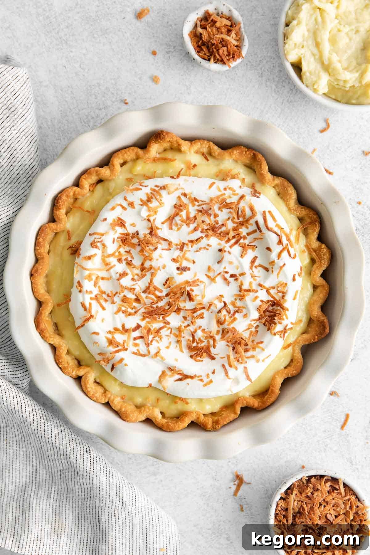 Vegan Coconut Cloud Pie 2 Dairy-free coconut cream pie surrounded by coconut shreds and cream in a bowl