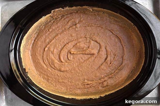 Creamy Homemade Slow Cooker Refried Beans 3 Refried beans in a black crock pot