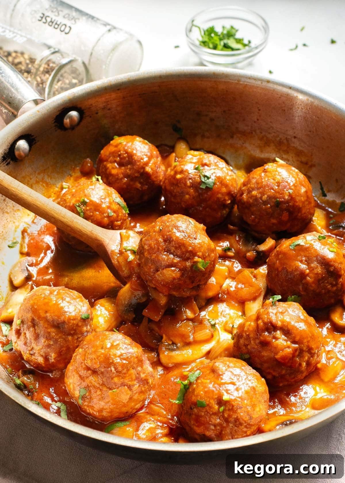 Classic Salisbury Steak Bites 2 Salisbury Steak Meatballs in skillet with spoon, ready to serve.