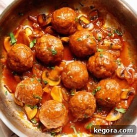 Salisbury Steak Meatballs and gravy in a skillet, garnished with fresh herbs.