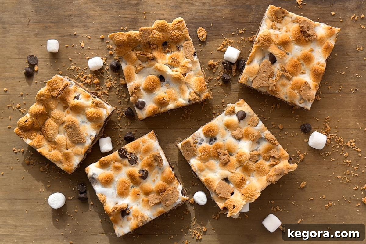 Ultimate Smores Bars 3 A top-down view of five perfectly cut S'mores Bars arranged on a wooden serving board, showcasing their distinct layers.