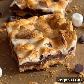A single S'mores Bar with a perfect toasted marshmallow top and melted chocolate on a wooden board.