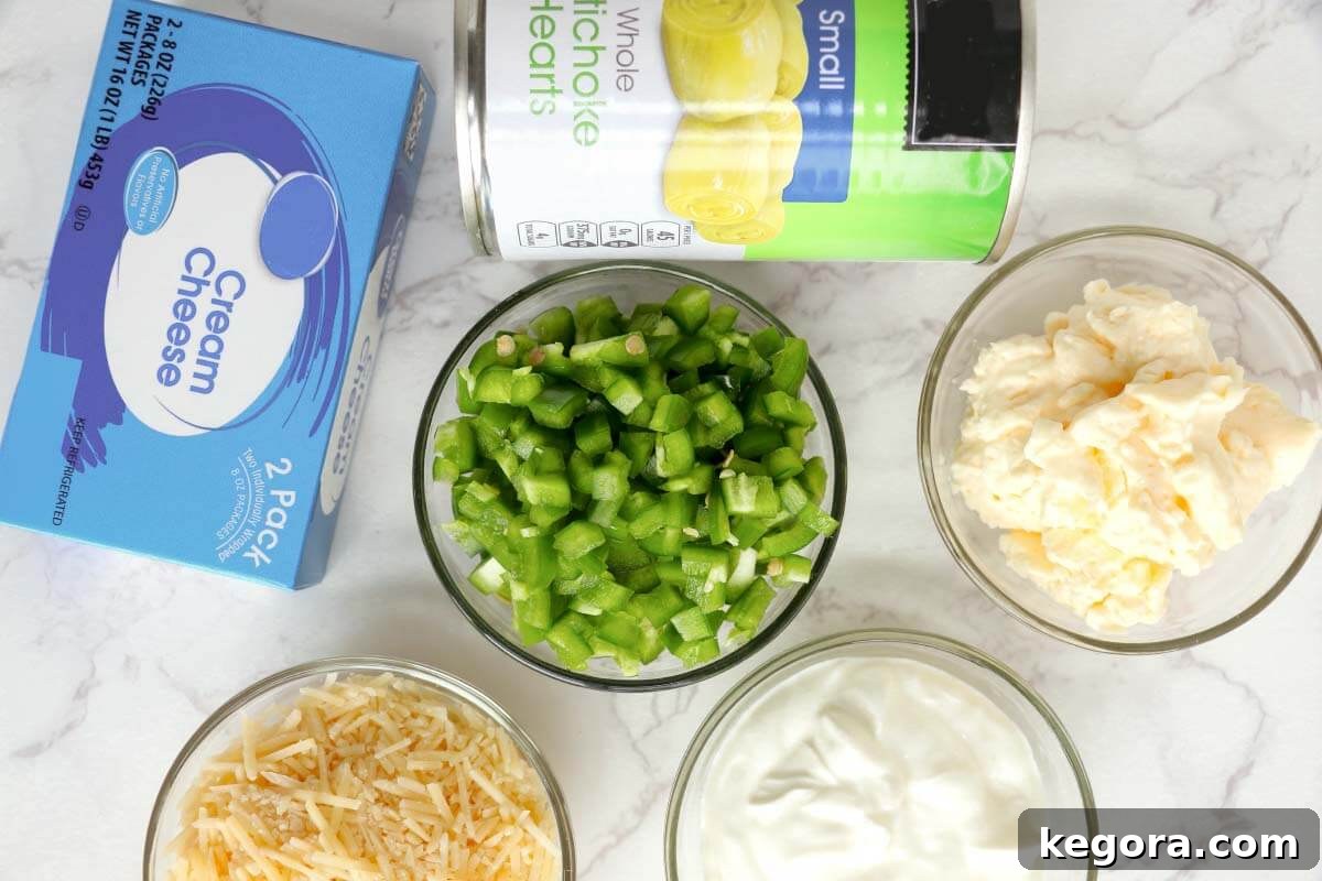 Baked Artichoke Jalapeño Dip ingredients laid out on a table: cream cheese, mayonnaise, sour cream, parmesan, jalapeños, and canned artichoke hearts.