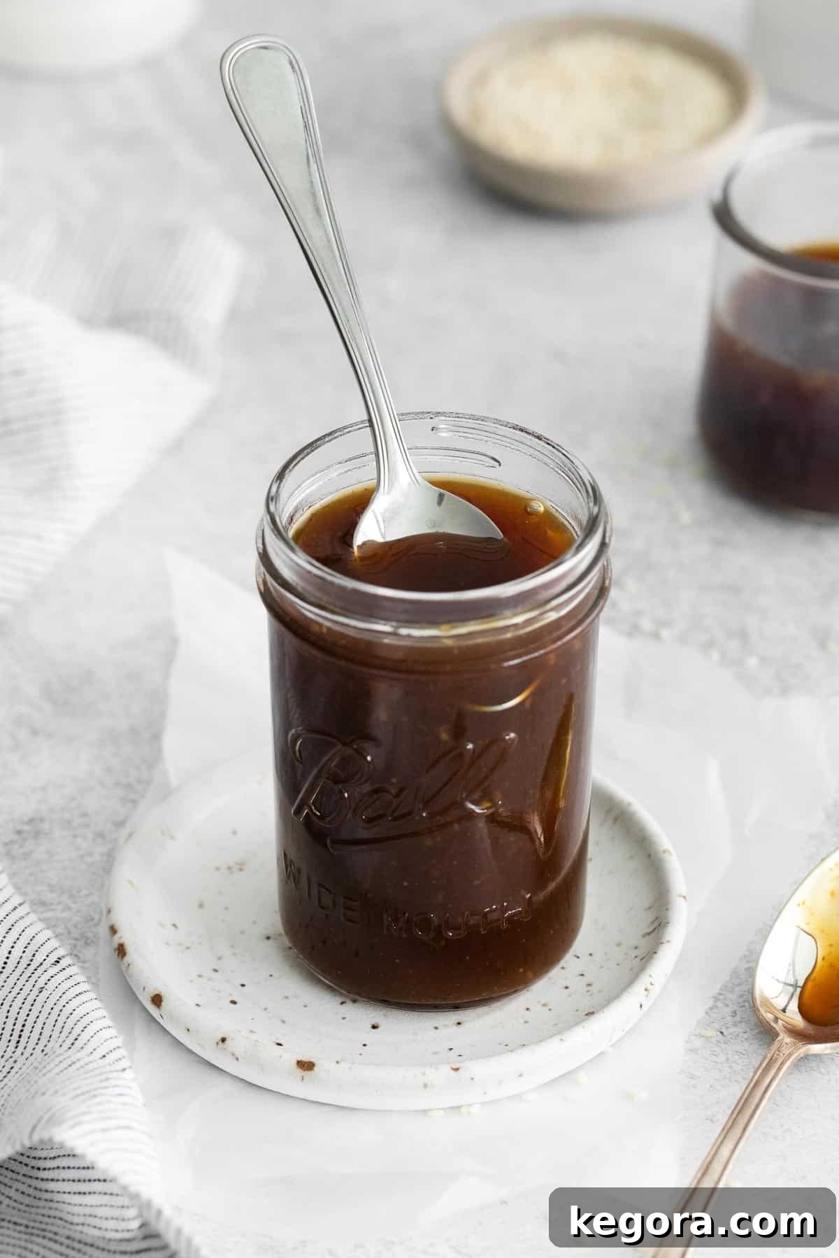 A spoon dipping into a jar of gluten-free teriyaki sauce