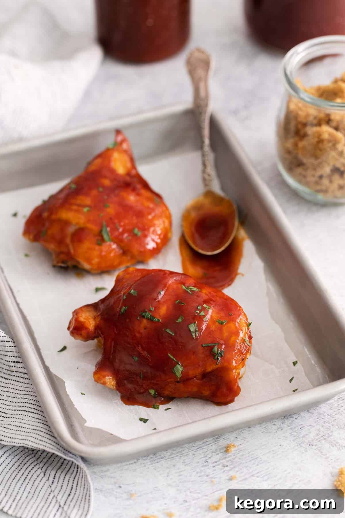 Gluten-free BBQ sauce spread over chicken on a baking sheet
