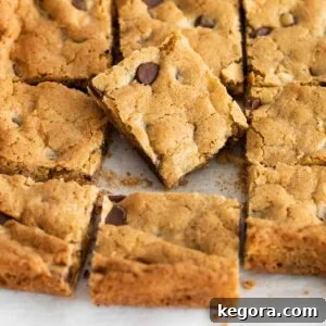A close up of blondies sliced in a sheet pan, with one piece placed on top of the others
