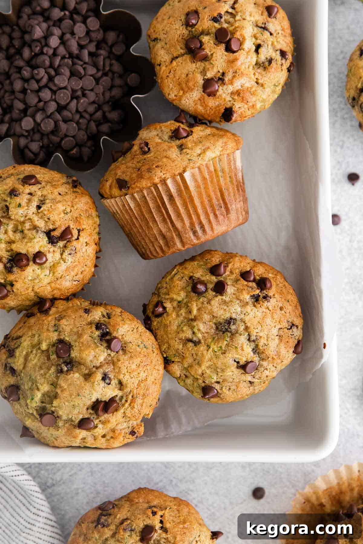 Three perfectly baked gluten-free zucchini muffins cooling on a wire rack, showcasing their golden-brown tops and moist interior, ready to be enjoyed.