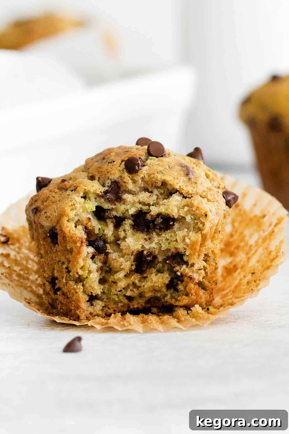 Scrumptious Gluten Free Zucchini Muffins 8 Close-up of a gluten-free zucchini muffin with a bite taken out, showing its moist and tender interior with mini chocolate chips