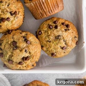 A close-up shot of golden-brown gluten-free zucchini muffins baking in a pan, showcasing their perfect dome tops and inviting texture.