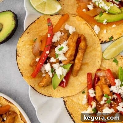 chicken fajitas on a white scalloped plate with lime and avocado.