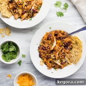 chicken and rice in white bowl with fork topped with cheese