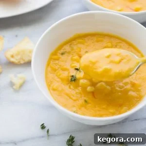 bowl of corn soup in white bowl with spoon taking bite