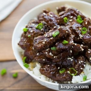 beef teriyaki over rice in white bowl topped with scallions