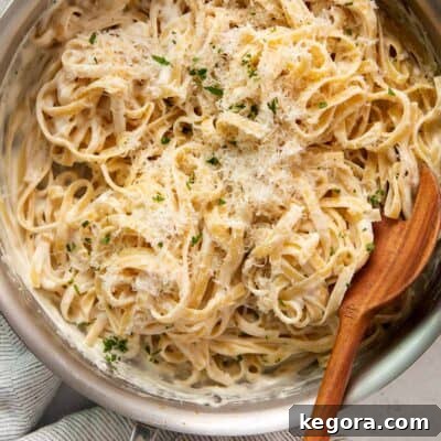 alfredo sauce in a metal bowl with a wooden spoon.