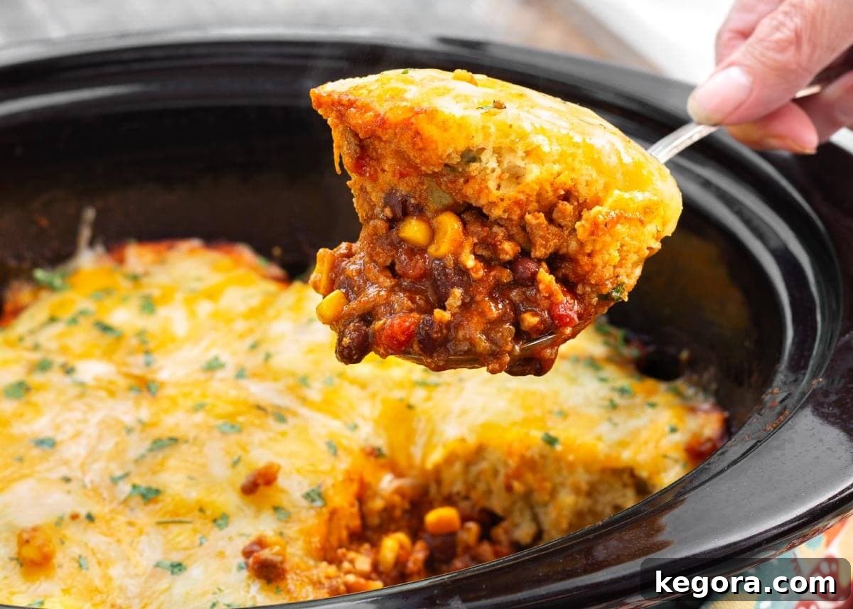 Slow Cooker Tamale Pie on a spoon above crock.