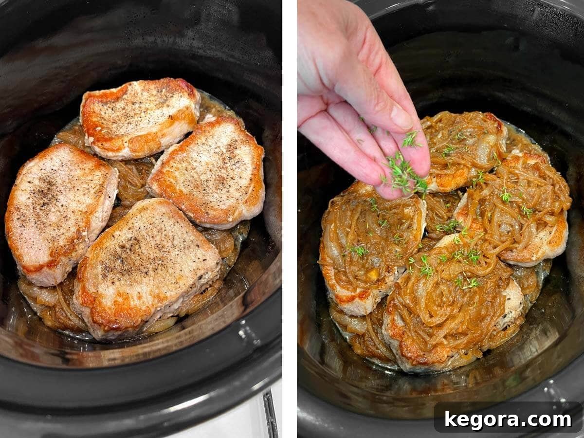 Seared pork chops placed over caramelized onions in a slow cooker, with fresh thyme sprigs added.