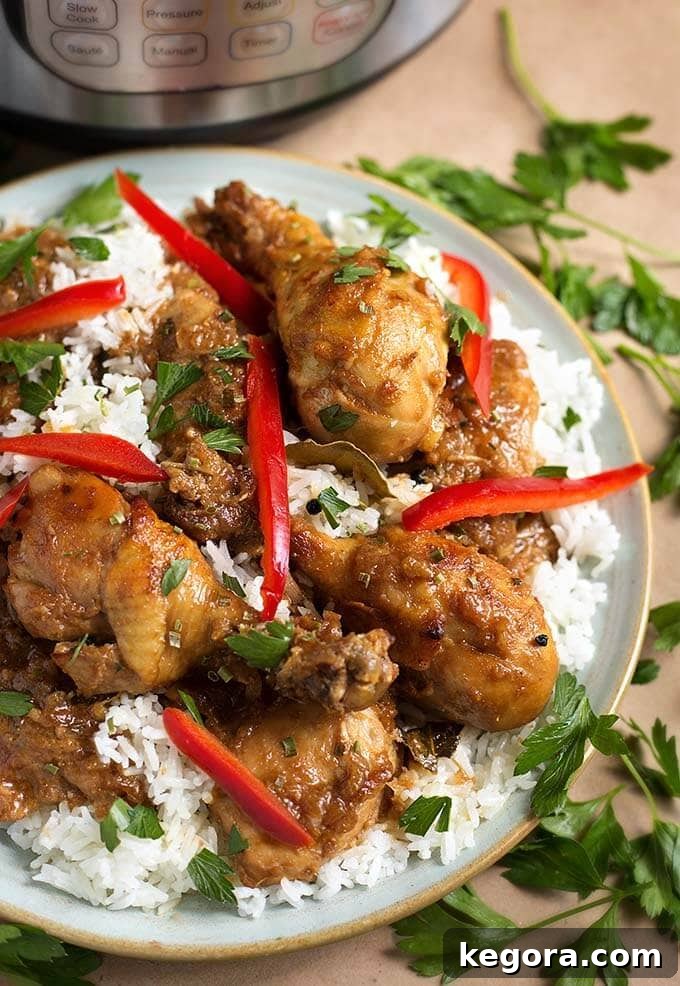 A vibrant plate of Instant Pot Chicken Adobo Filipino with fluffy white rice, garnished with fresh red bell peppers and cilantro, ready to be enjoyed.