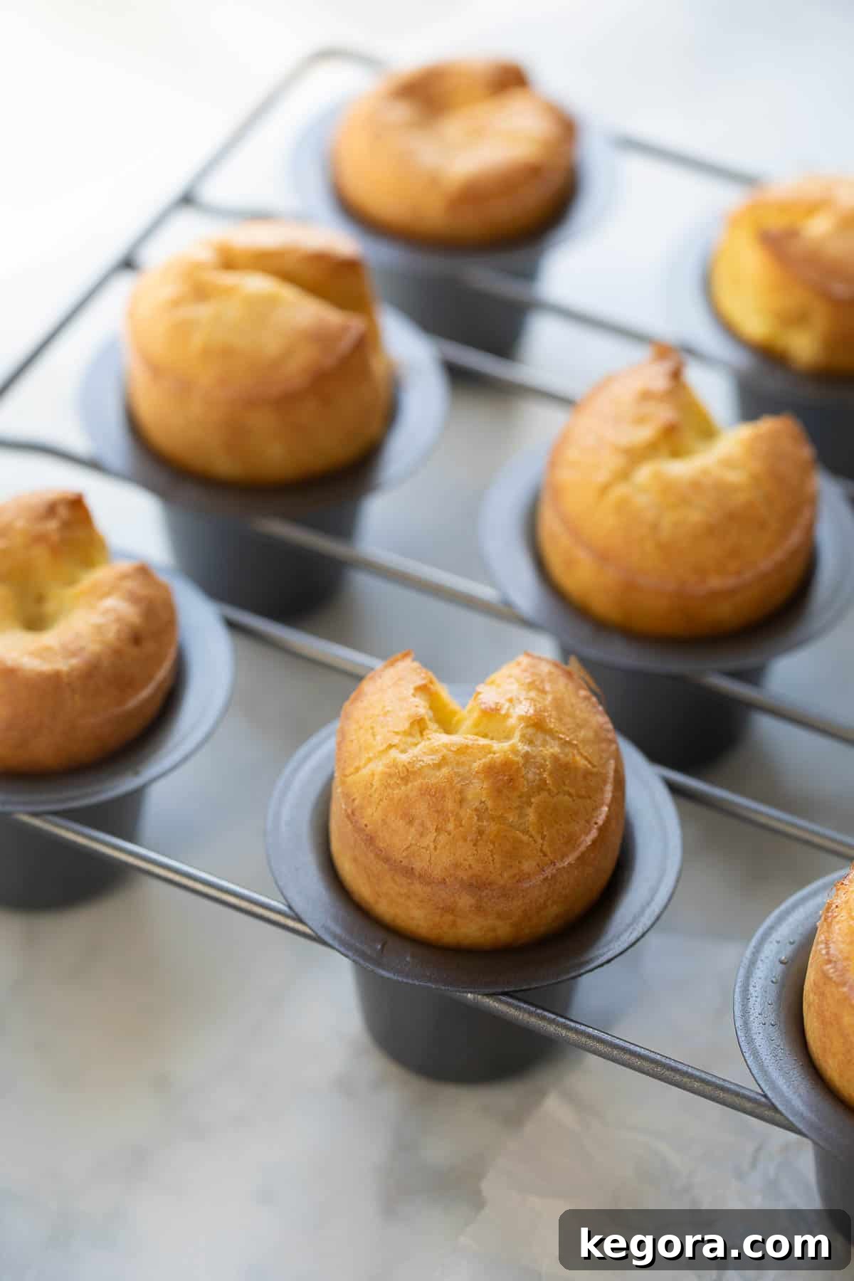 Gluten-Free Popovers Freshly baked golden-brown gluten-free popovers still in the muffin pan, showcasing their impressive rise and airy structure.