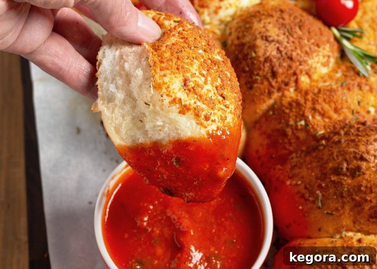 dipping Dinner Roll Christmas Tree Appetizer in marinara sauce.