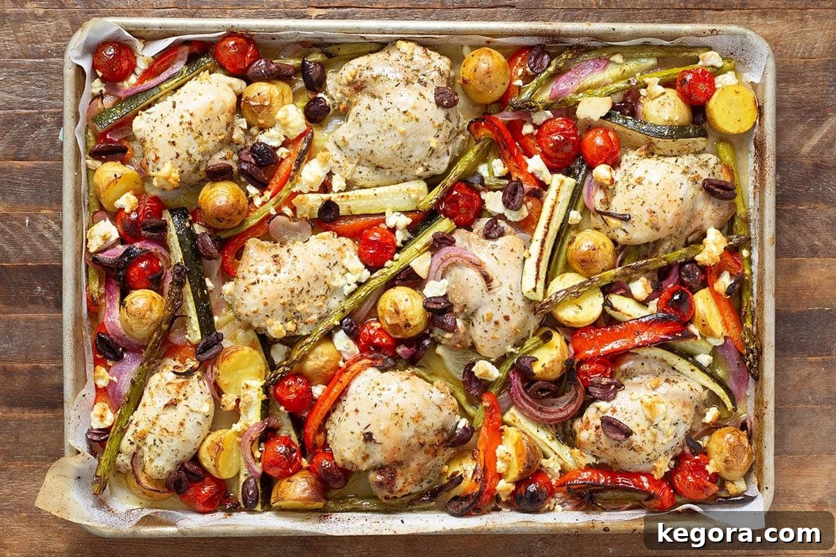 One-Pan Greek Lemon Herb Chicken 10 Sheet pan with Greek chicken thighs, potatoes, cherry tomatoes, olives, and feta