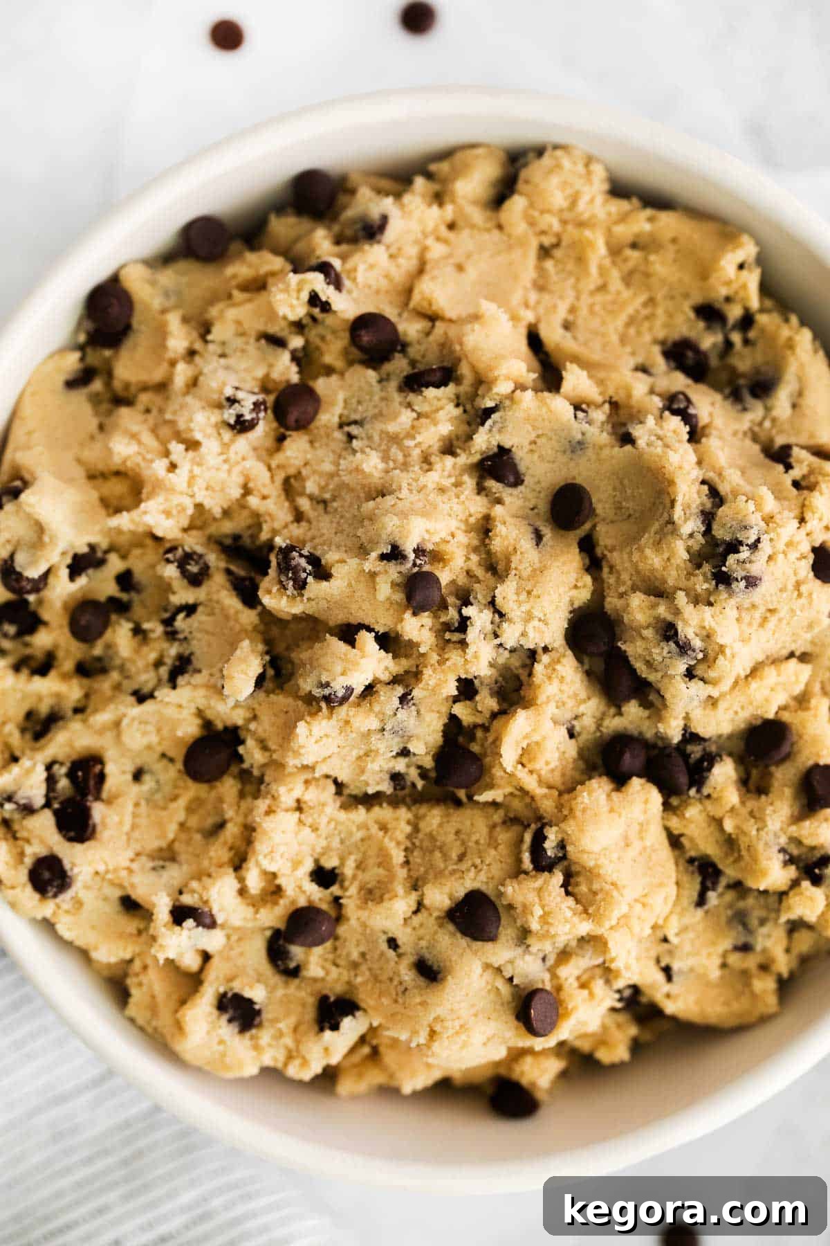 Guiltless Gluten-Free Cookie Dough Cravings 3 A close-up of creamy edible gluten-free cookie dough in a rustic bowl, generously studded with mini chocolate chips, ready for a spoon.