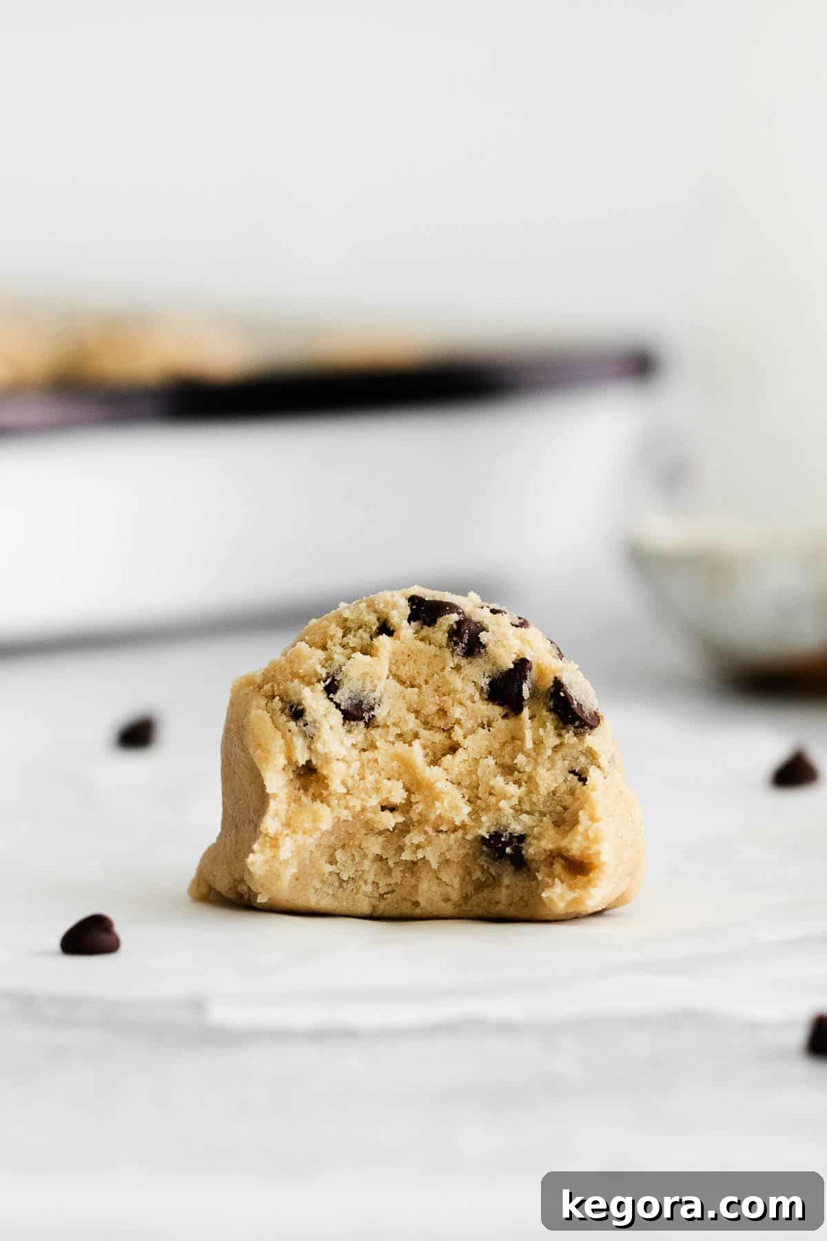 Safe and Scrumptious Gluten-Free Cookie Dough 8 A close-up of a single perfectly formed gluten-free edible cookie dough ball with a bite taken out, revealing its creamy texture and abundant mini chocolate chips