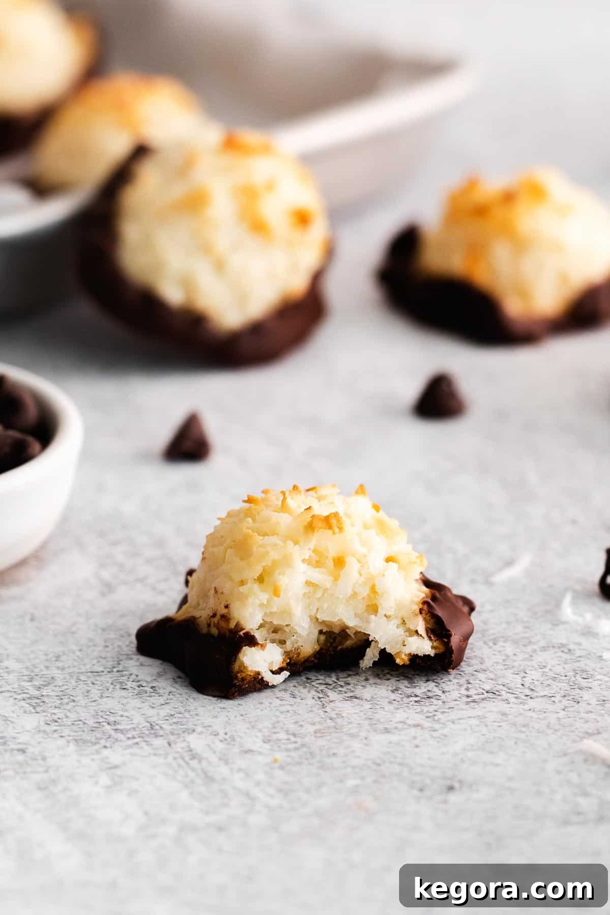 Golden Coconut Cloud Cookies 9 A gluten-free macaroon with a bite taken out, on parchment paper