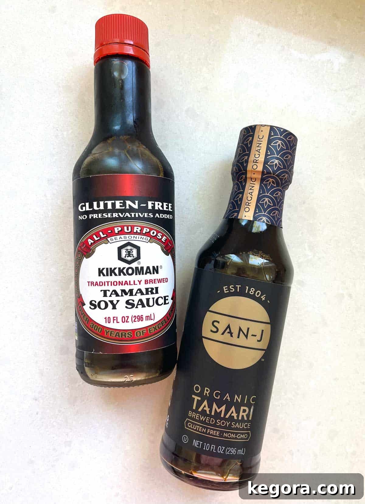 Overhead shot of two distinct bottles of soy sauce, highlighting the difference between traditional and gluten-free options on a clean white counter.