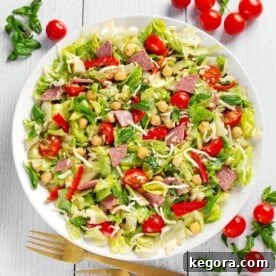 Italian Chopped Salad on white plate with tomatoes, basil, salami, lettuce