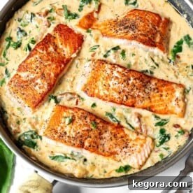 Four Creamy Garlic Tuscan Salmon fillets in a pan of sauce.