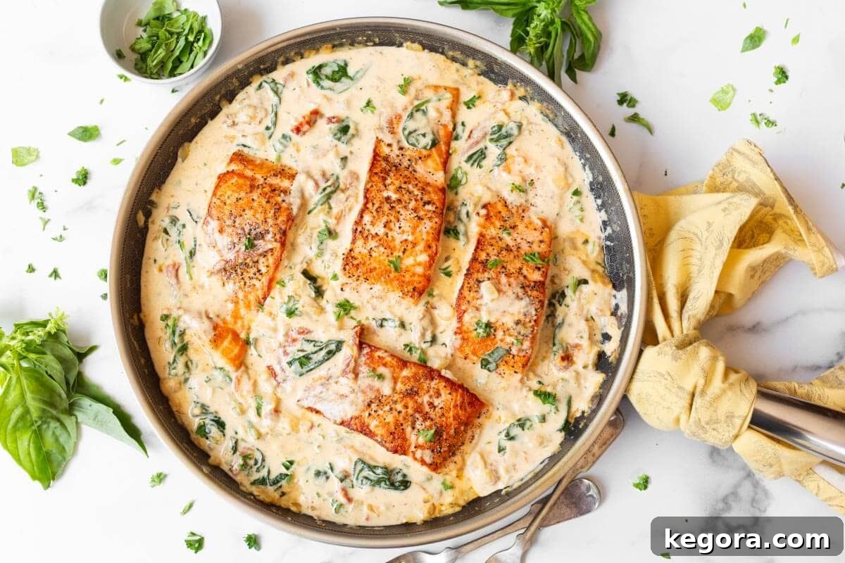 Decadent Creamy Garlic Tuscan Salmon 10 Four beautifully cooked salmon fillets bathed in the rich, creamy Tuscan sauce in a large pan, ready to serve.