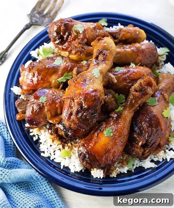 Delicious Slow Cooker Sticky Chicken Drumsticks served with fluffy white rice on a blue plate, ready to be enjoyed.