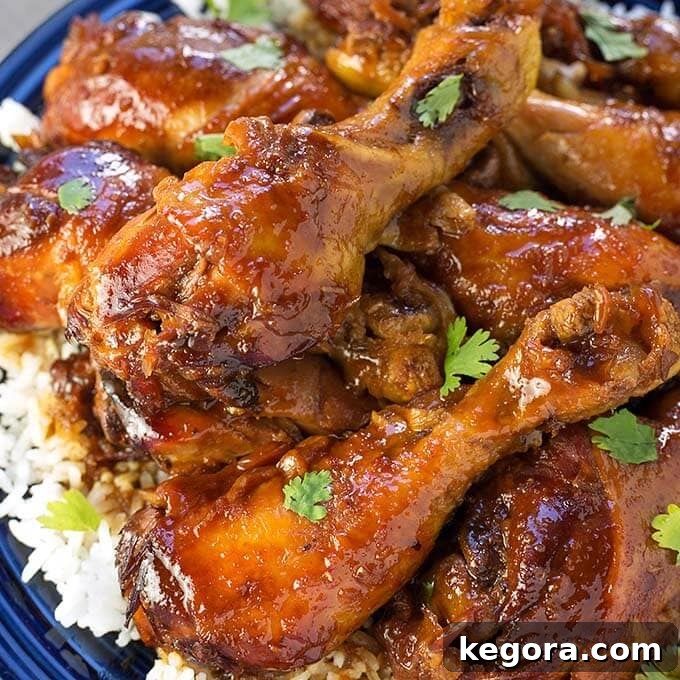 Close-up view of a succulent Sticky Chicken Drumstick served over rice on a vibrant blue plate, showcasing the rich glaze.