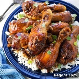 Sticky Chicken Drumsticks with rice on a blue plate next to silver fork, highlighting the delicious meal.
