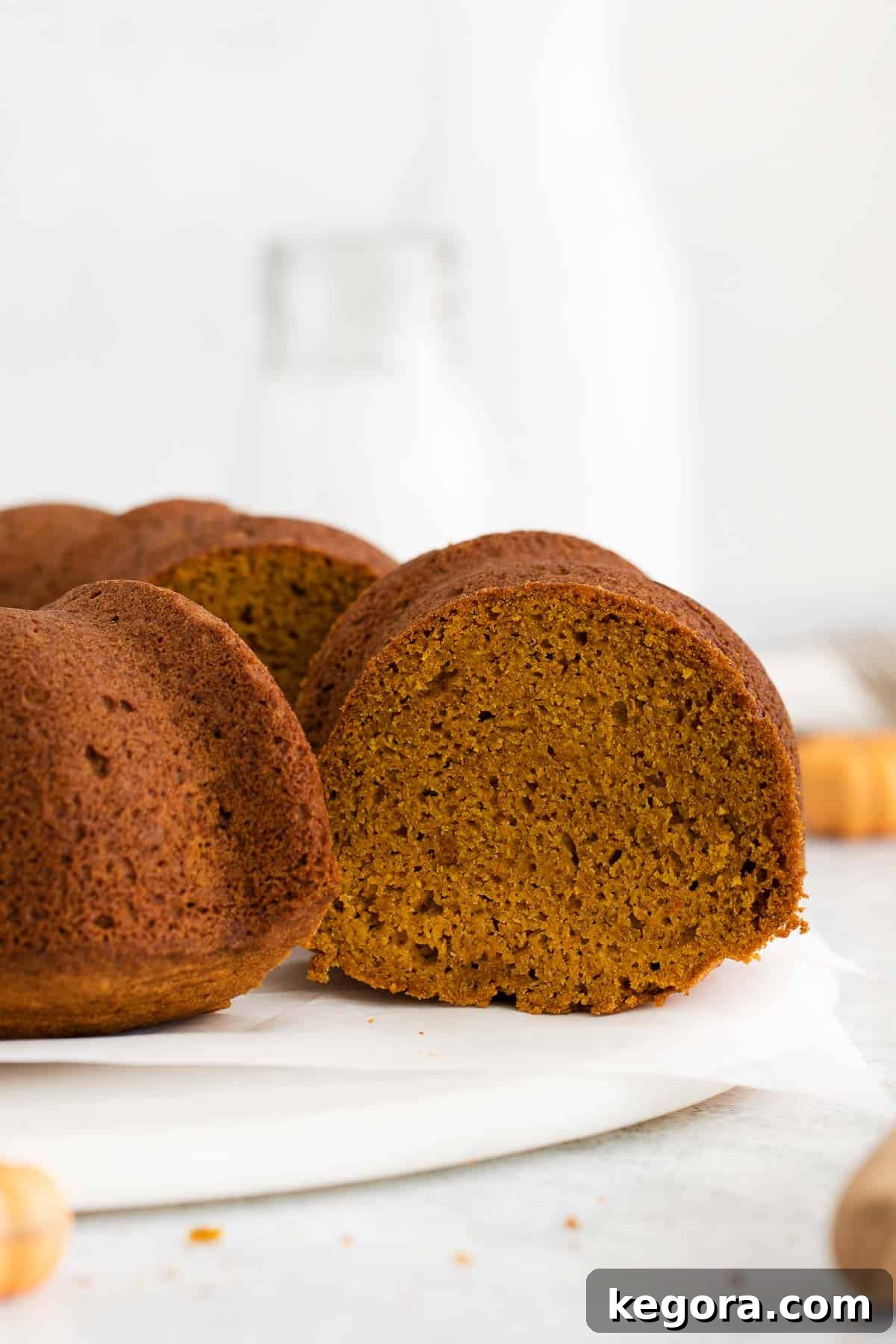A side view of a beautifully frosted gluten-free pumpkin cake on a elegant cake platter, ready to be served.