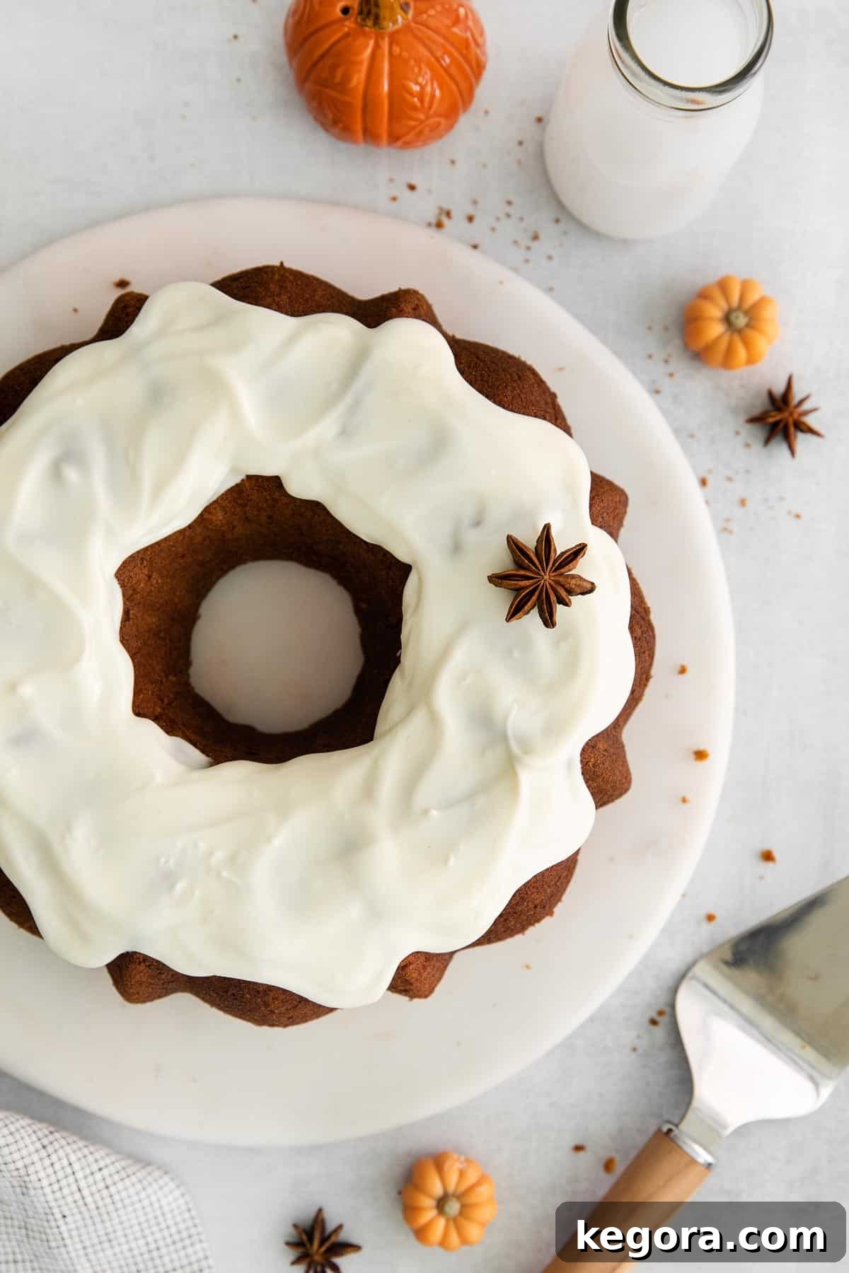 An overhead view of a perfectly frosted gluten-free pumpkin cake, adorned with cream cheese icing, ready for serving.