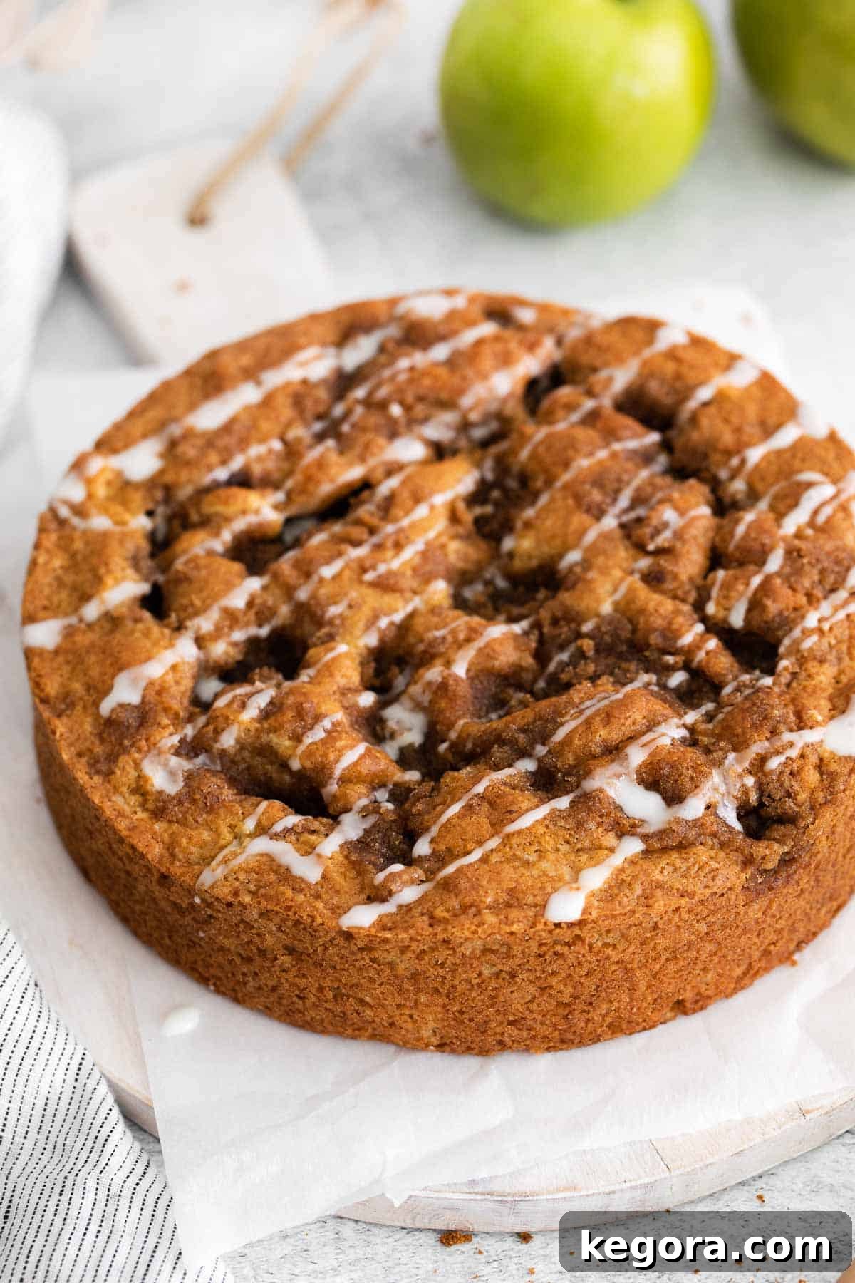 Homestyle Gluten-Free Apple Cake 2 A whole, golden-brown gluten-free apple cake with a crumble topping, sitting on a rustic kitchen countertop, ready to be sliced.