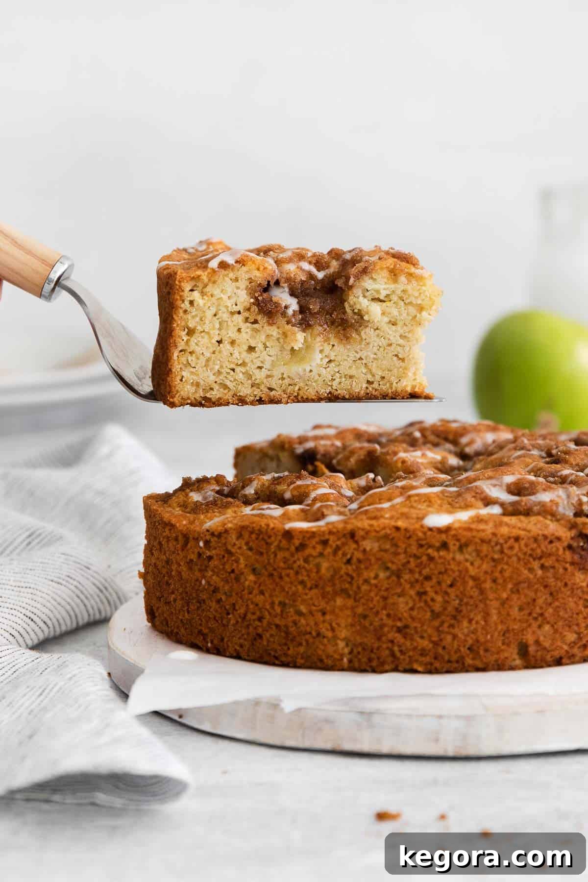Homestyle Gluten-Free Apple Cake 12 A spatula carefully removing a perfect slice of gluten-free apple cake from the pan, highlighting its beautiful layers and texture.