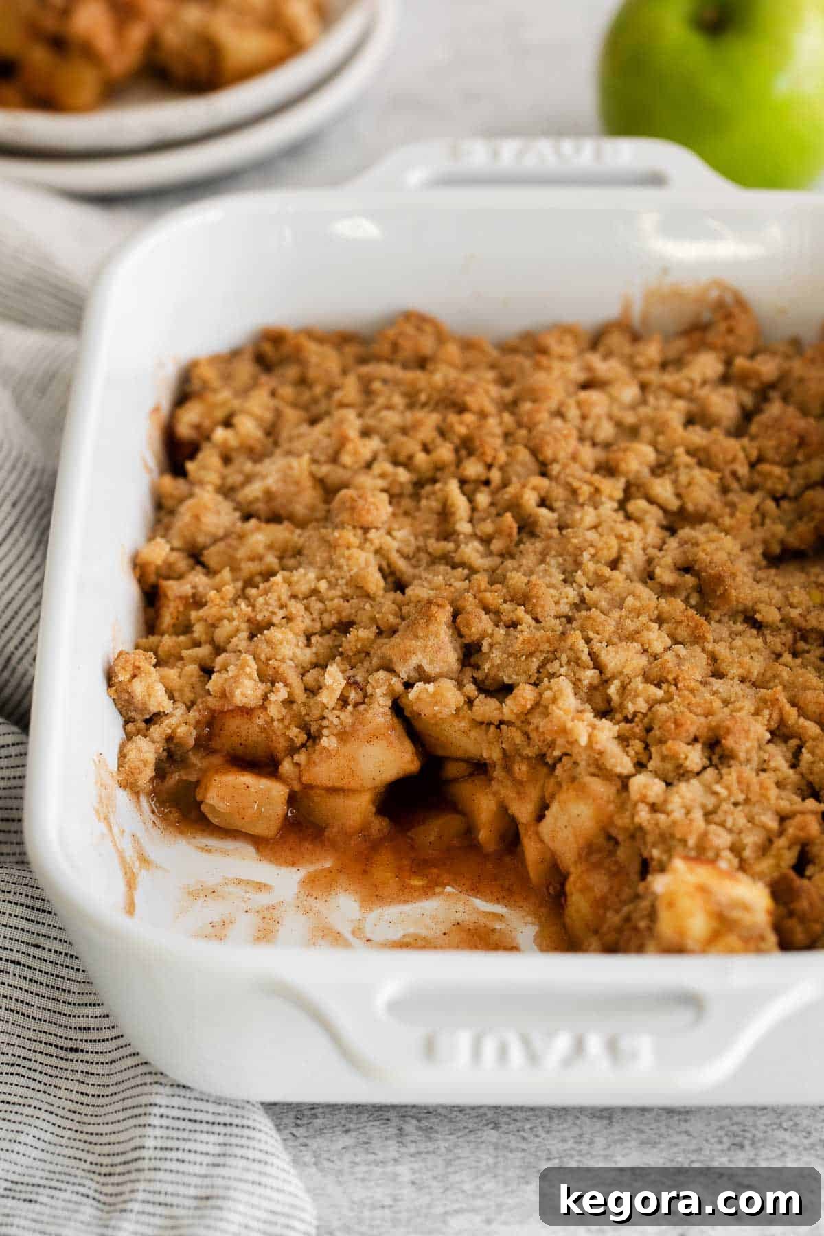 A dish of apple crumble, with a serving scooped out