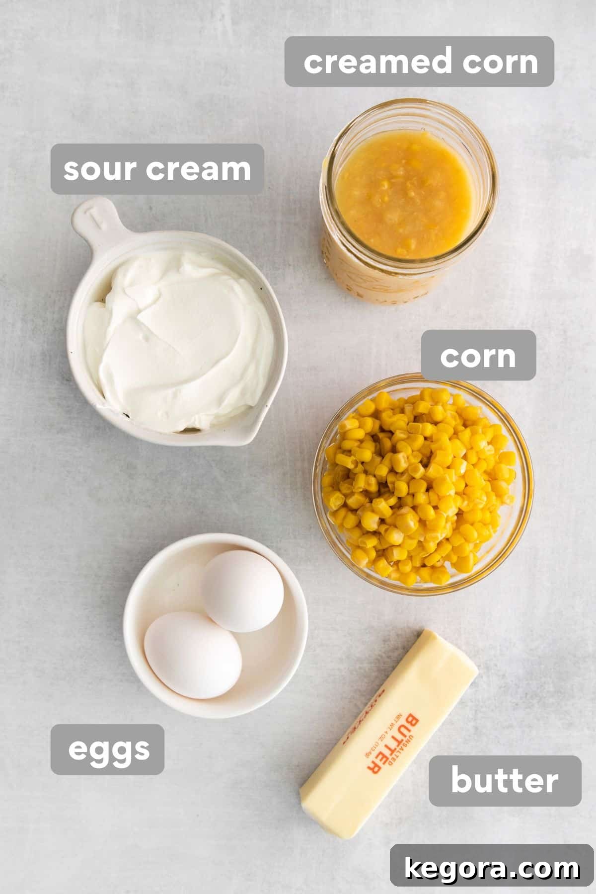 Creamy Gluten-Free Corn Bake 4 All the wet ingredients for gluten-free corn casserole laid out on a clean counter top, including canned creamed corn, whole corn, sour cream, and butter
