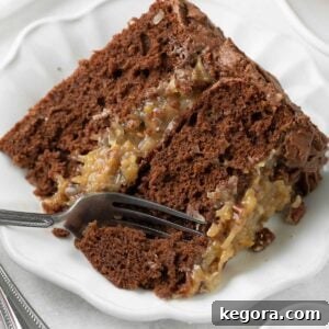 Decadent Gluten-Free German Chocolate Cake 11 A tempting slice of German chocolate cake, showcasing its rich chocolate layers and irresistible coconut-pecan frosting, with a fork ready for a bite.