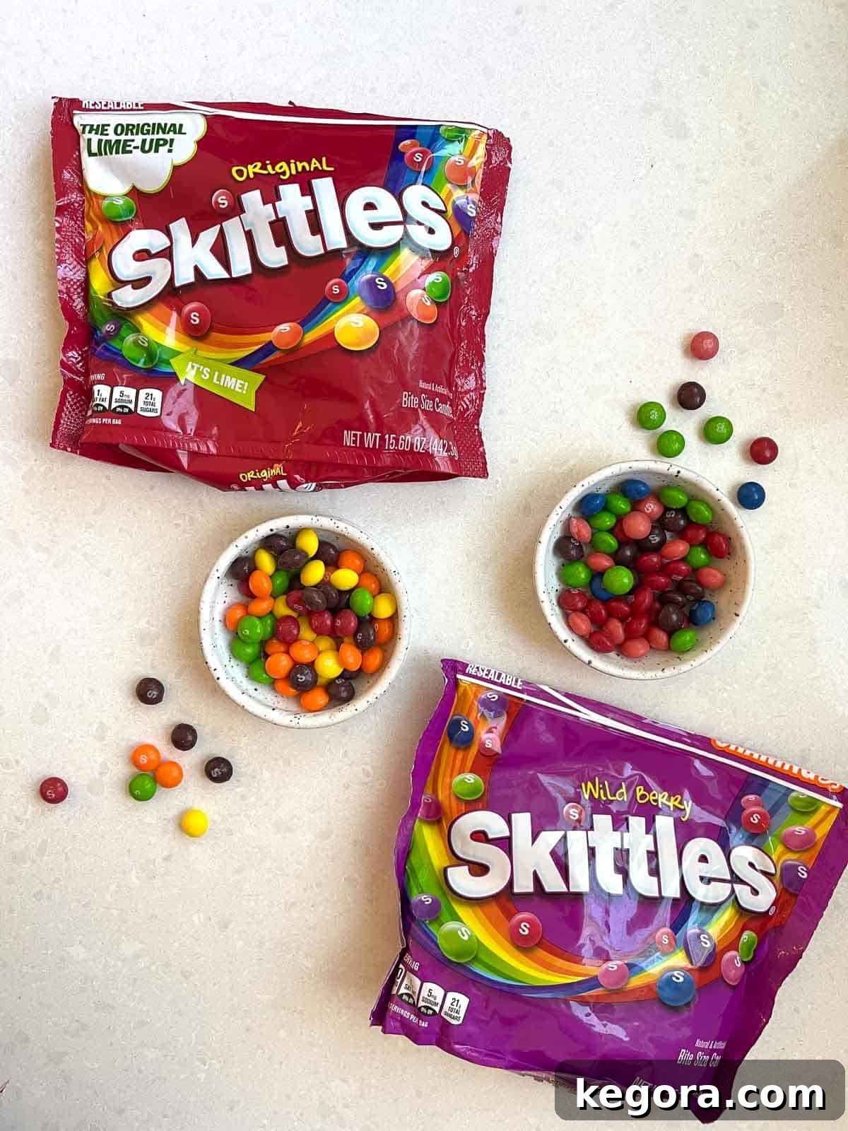 Can You Eat Skittles on a Gluten-Free Diet 3 Two bags of Skittles and two bowls filled with colorful Skittles candy on a white counter, emphasizing their gluten-free status.