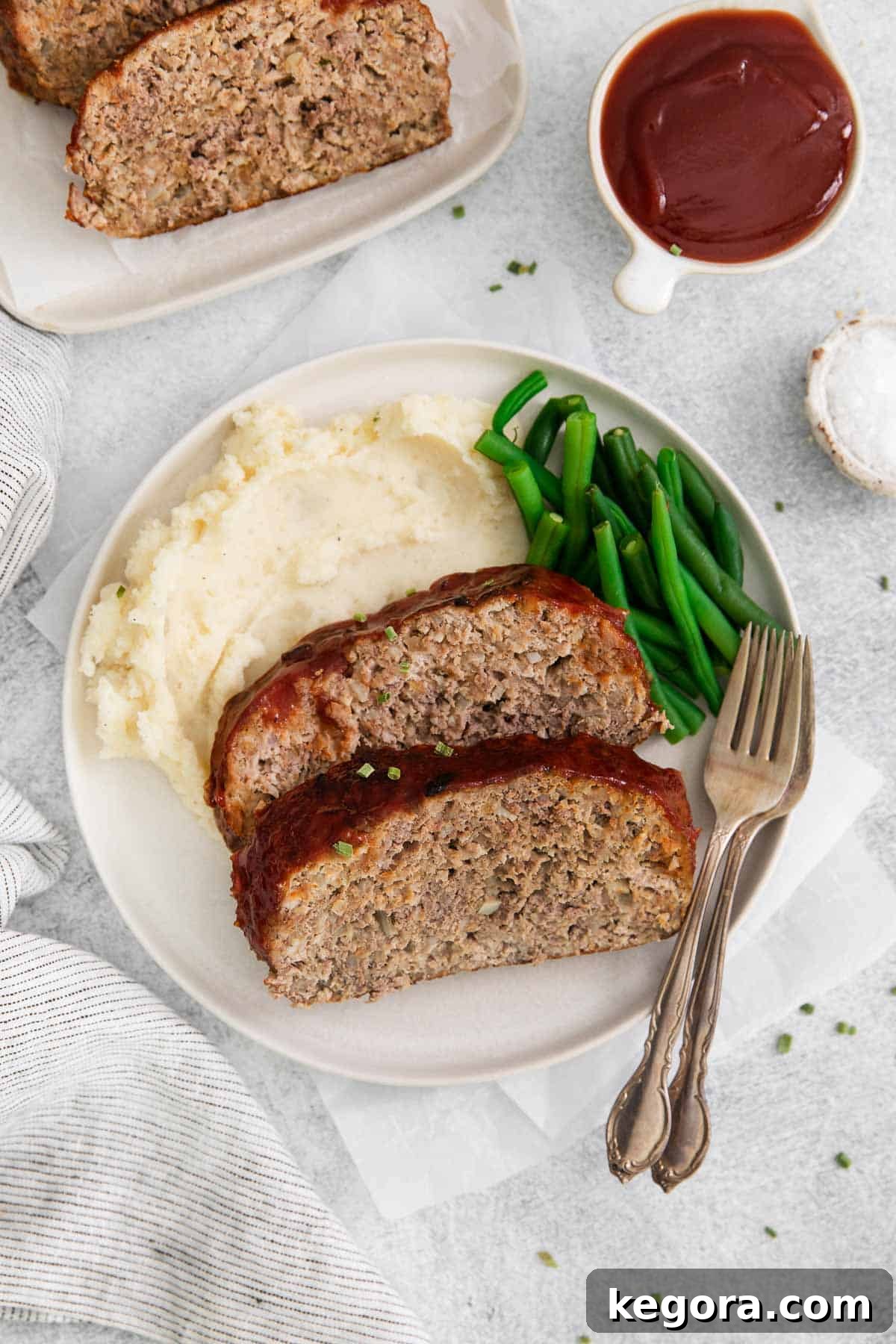Gluten-free meatloaf arranged on a plate with mashed potatoes and green beans
