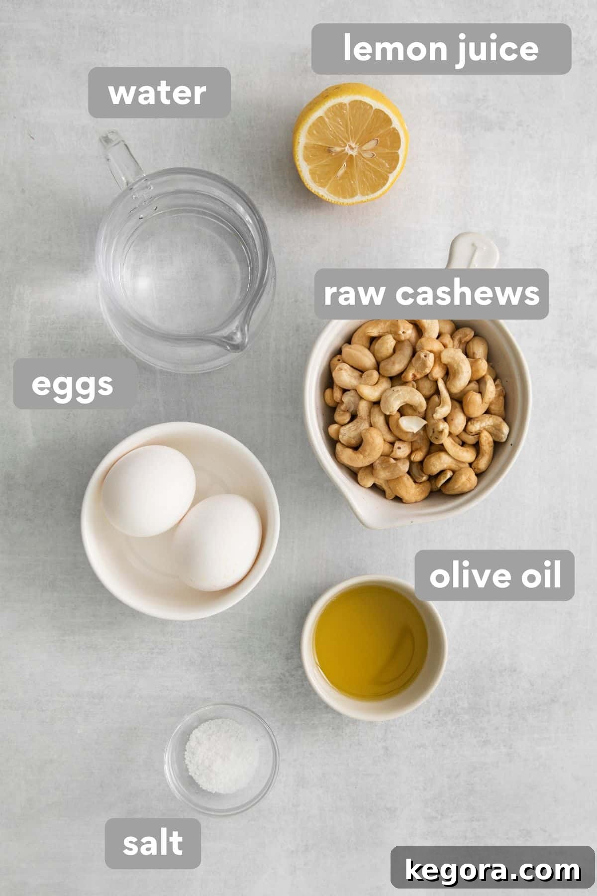 Luscious Dairy-Free Lasagna 4 Ingredients for the dairy-free cashew cream sauce, including raw cashews, eggs, olive oil, and lemon juice, arranged on a countertop.