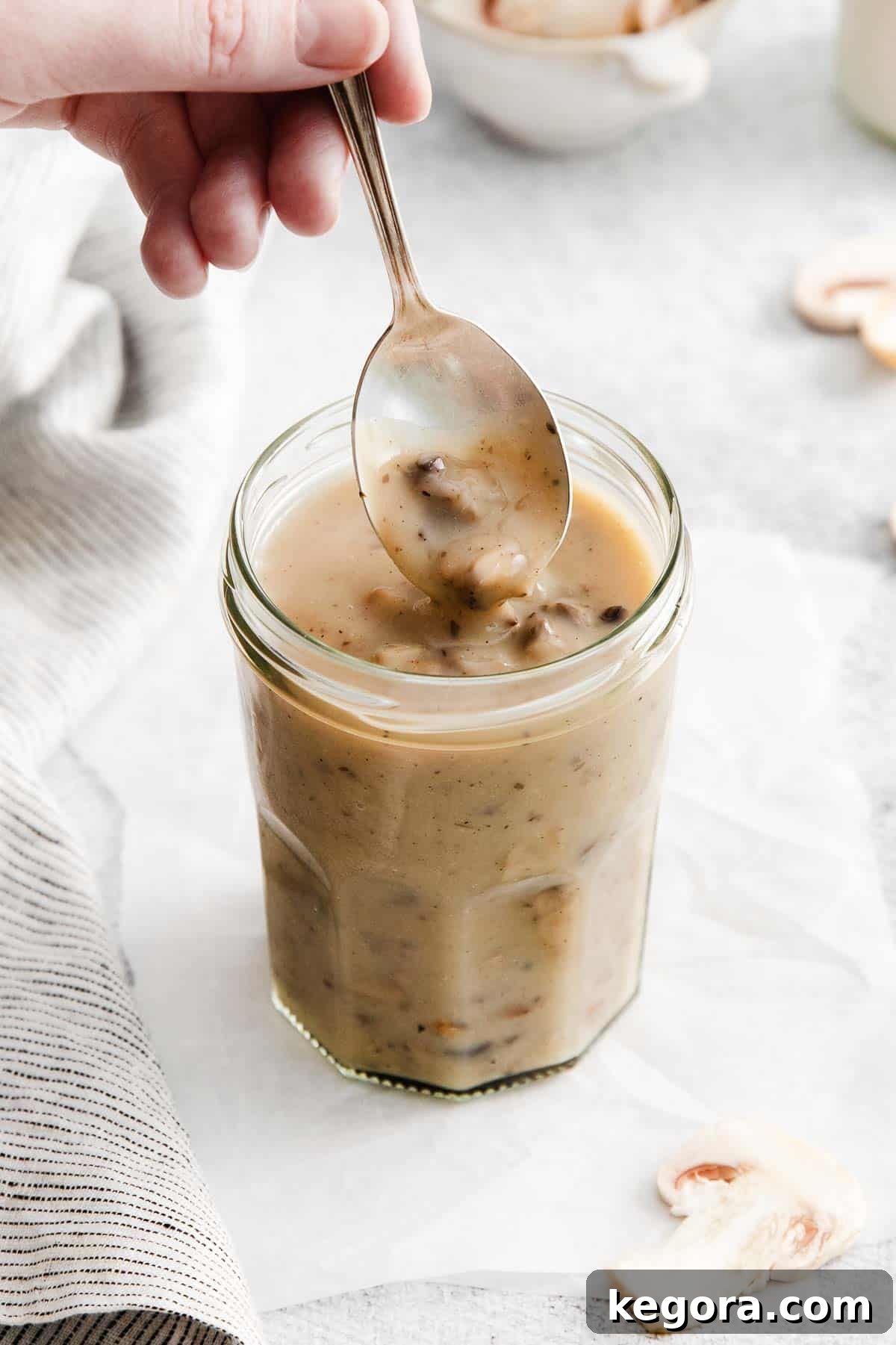 Velvety Gluten-Free Mushroom Magic 3 A spoon dipping into a cup of homemade gluten-free cream of mushroom soup, highlighting its rich, creamy texture.