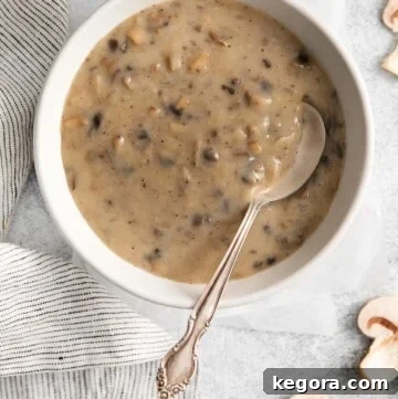 A bowl of cream of mushroom soup with a spoon in it, showcasing its creamy texture.